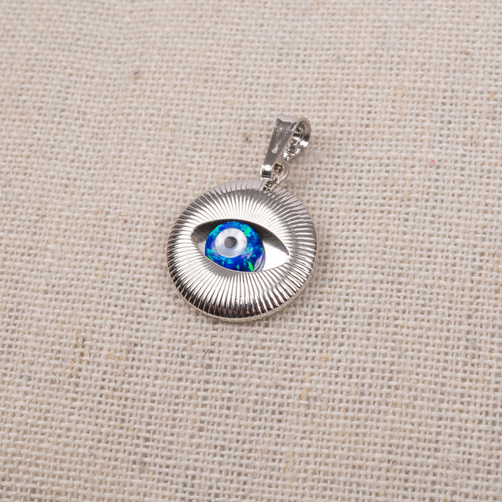 A silver pendant with a blue and white opal eye design on a textured background.