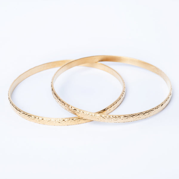 A pair of yellow gold-plated stainless steel bangle bracelets designed with a filigree pattern.