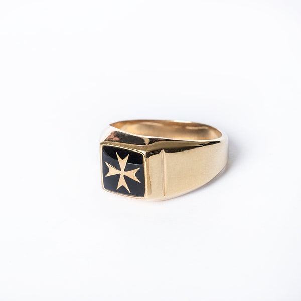 A gold-plated silver Gianni ring with a black Maltese cross emblem on it, displayed against a white background.