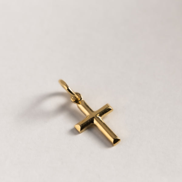 A gold embossed cross pendant on a plain background.