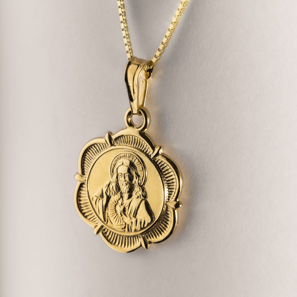 A gold double-sided Holy pendant with a religious figure in the center, displayed against a white background.