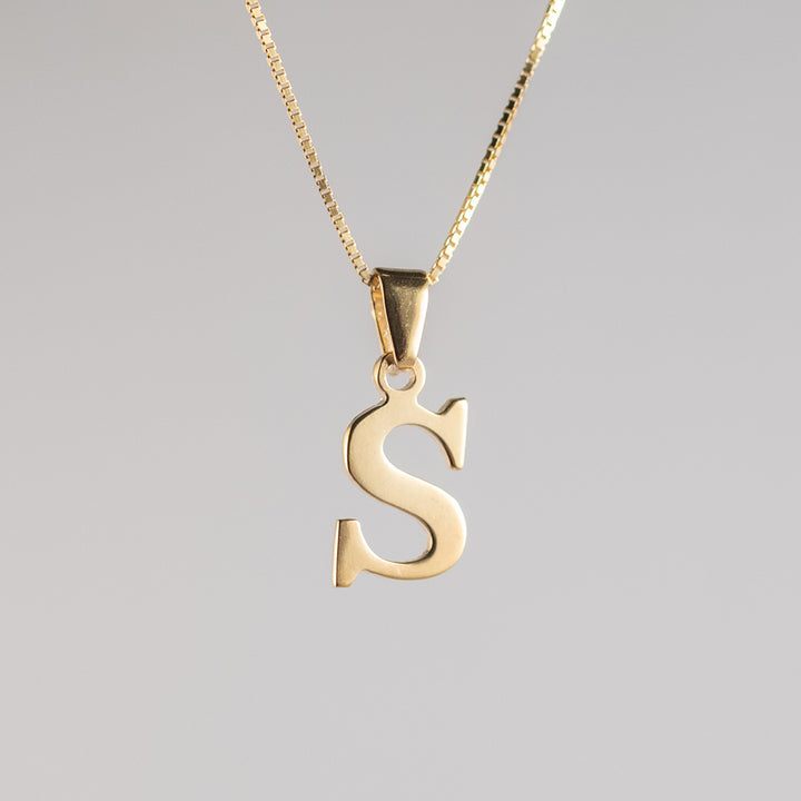 A gold-plated sterling silver pendant in the shape of the letter 'S' on a chain, against a white background.