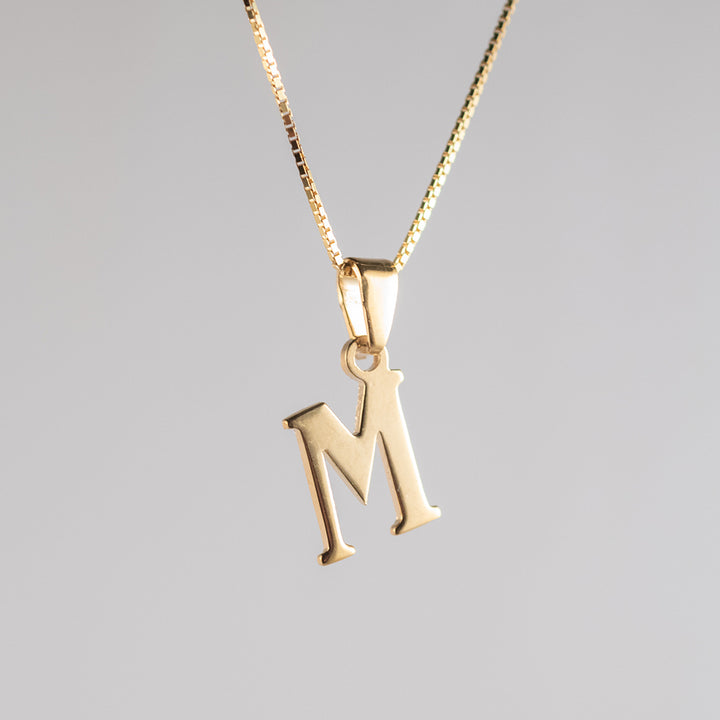 A close up view of initials gold M letter pendant letter 
