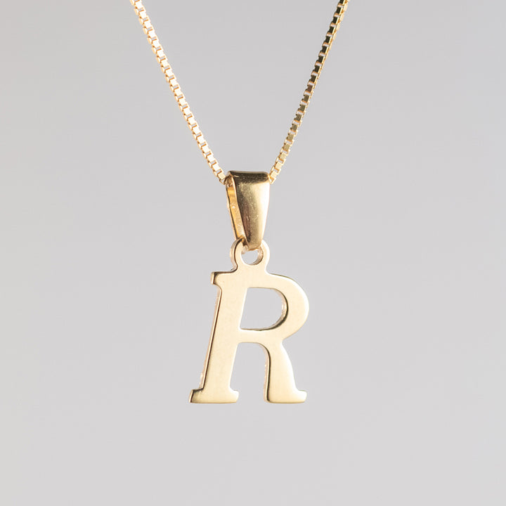 A close up view of R initials gold letter pendant letter 