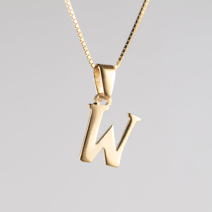 A close up view of initials gold letter pendant W letter 