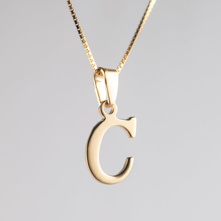 A close up view of initials gold letter pendant C letter 