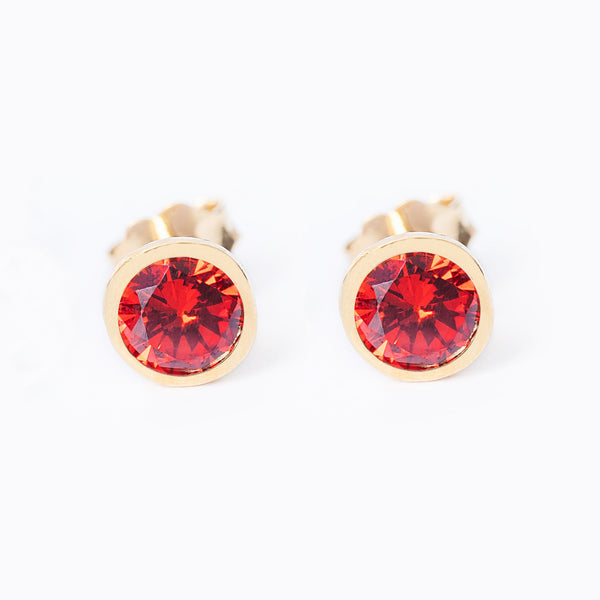 A pair of studJanuary Birth Stone earrings with red garnet gemstones set in yellow gold-plated silver.