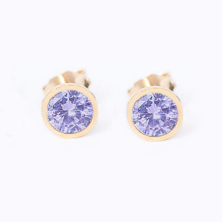 A pair of round June Birth Stone earrings with a yellow gold plated finish and a central amethyst lilac gemstone.