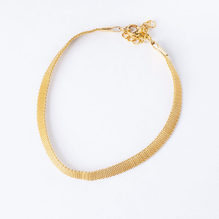 Gram collections's maderia bracelet in gold colour standing in the center of the image, against a white background, seeing  from a bird view perspective. 