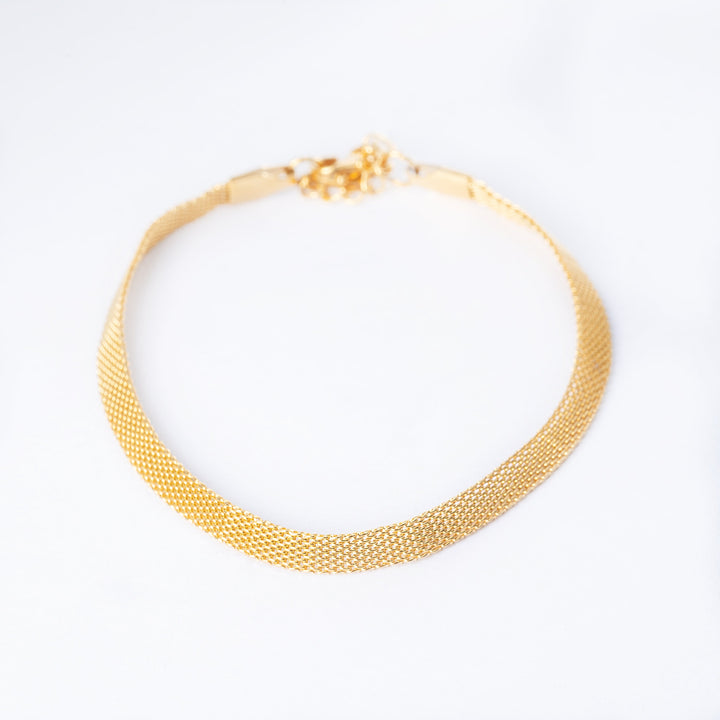 A yellow gold-plated stainless steel bracelet with a solid pattern and a gold-tone clasp.