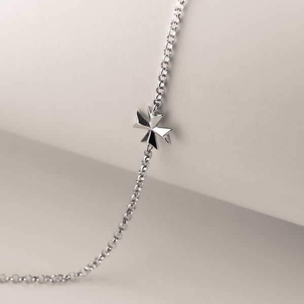 A silver Malta cross bracelet featuring a single star-shaped charm, displayed on a chain against a mannequin bust.