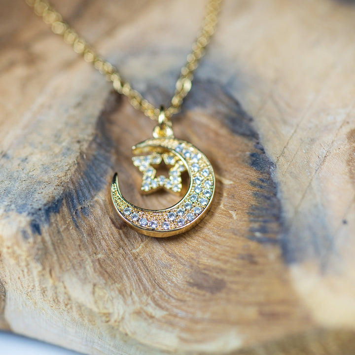 A close up view of Moon & Star Gold Pendant standing in the center of the image against a white background 