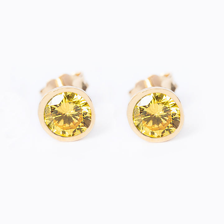 A pair of yellow gold plated silver November bird stone earrings with a citrine yellow gemstone in a sunburst design.