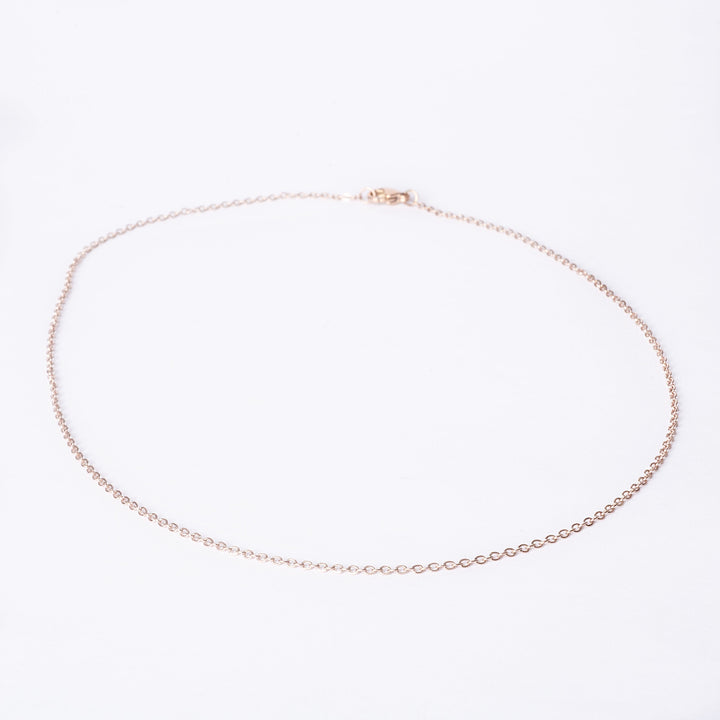 Bird view of  rose gold chain standing in the center of the image against a white background. 