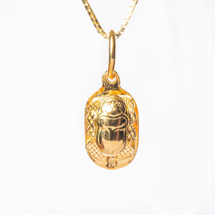 A close up view of Scarab Necklace pendant, standing in the center of the image against a white background. 