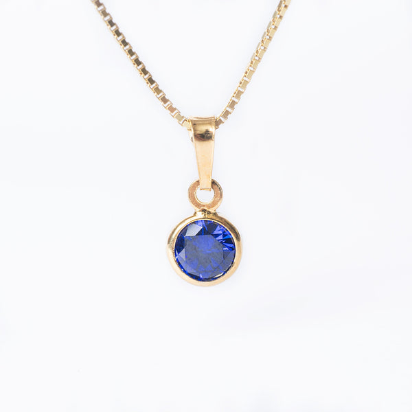 A yellow gold-plated silverSeptember Birth Stone pendant featuring a blue sapphire gemstone, attached to a gold-plated chain.