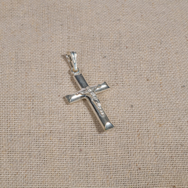 A silver-colored cross pendant on a textured background.