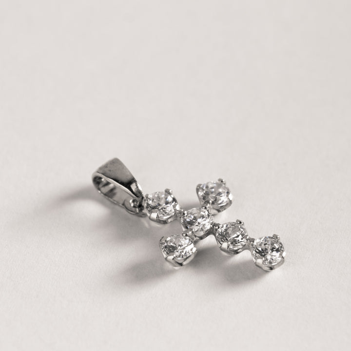 A silver-colored zirconia cross pendant on a plain background.