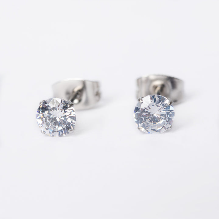 A close up view of Solitaire Silver Stud Earrings in white colour stone, standing in the center of the image against a white backgronnd. 