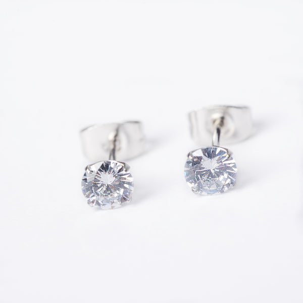A pair of silver stud earrings featuring a clear, cubic zirconia gemstone in a classic six-prong setting.