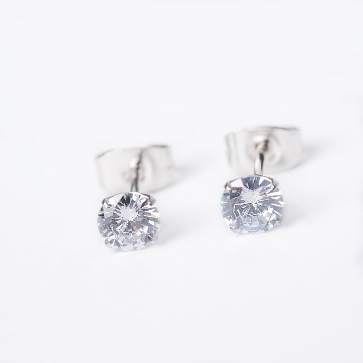 A pair of silver stud earrings featuring a clear, cubic zirconia gemstone in a classic six-prong setting.