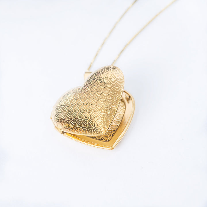 A close up view of half-open heart pendant, standing in the center of the image against a white background. 