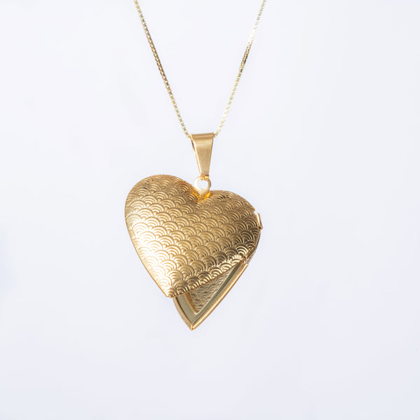 A gold-plated stainless steel locket in the shape of a heart, suspended from a chain.