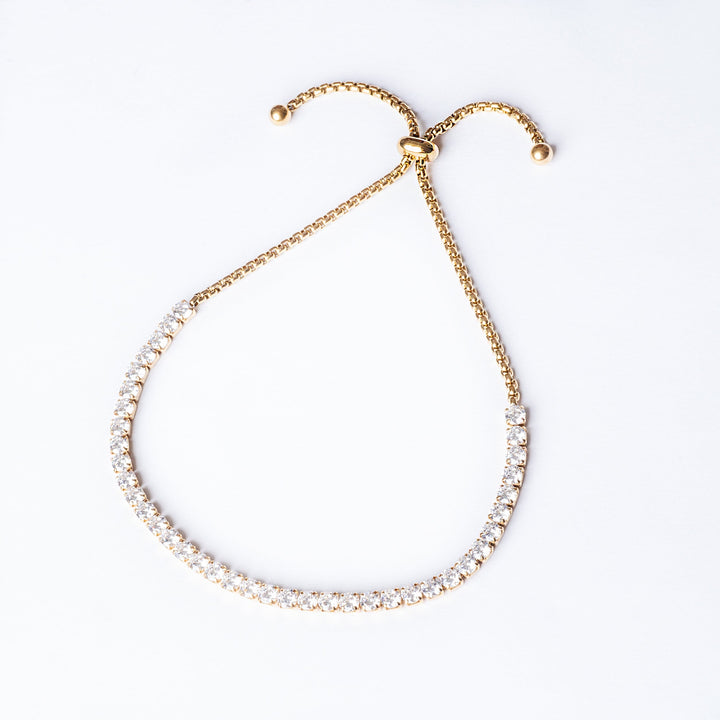 A close up view of Gram Collections's Tennis Gold bracelet, standing in the center of the image. 