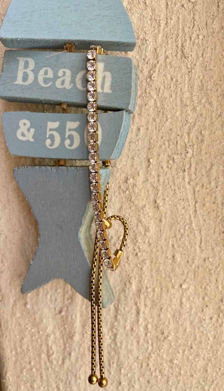 Tennis gold bracelet attached to wooden fish on the orange wall. 
