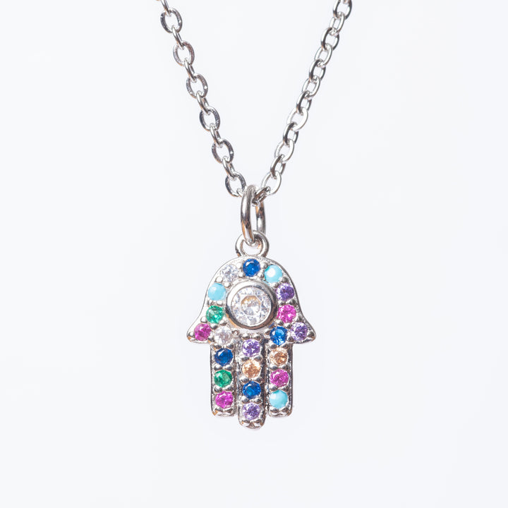 A close up view of The Hamsa Necklace standing against a white background. 