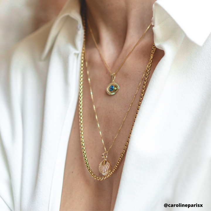 A woman wearing Evil Eye Pendant in combination with other pieces and her white shirt. 