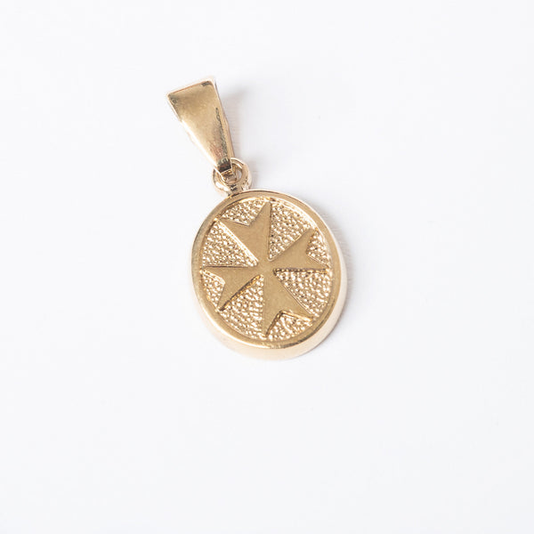 A gold-plated, circular-shaped pendant with a textured design, possibly a star, on a white background.