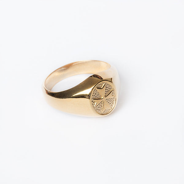 A gold-plated Xandru silver ring with a geometric pattern on the top part, set on a plain white background.